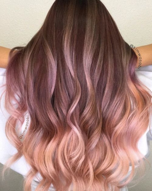 Long wavy hair fades from dark roots into rose pink and peachy blonde ends