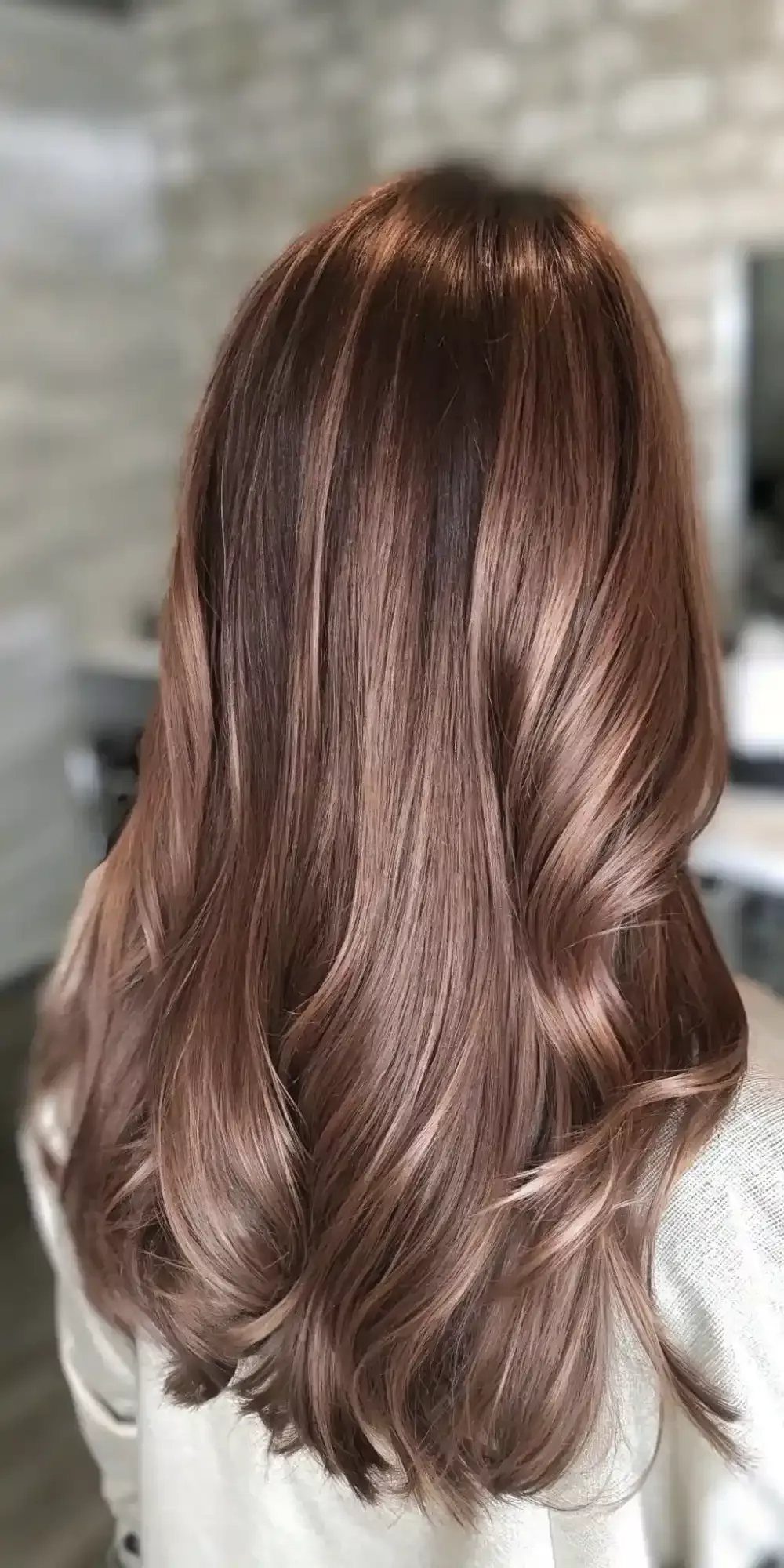 Long muted rose-gold hair with glossy flowing waves and curled ends