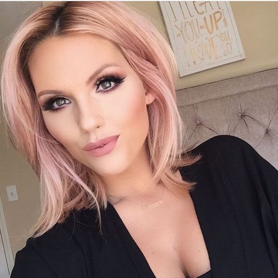 Woman with straight pale rose-pink layered hair and face-framing strands