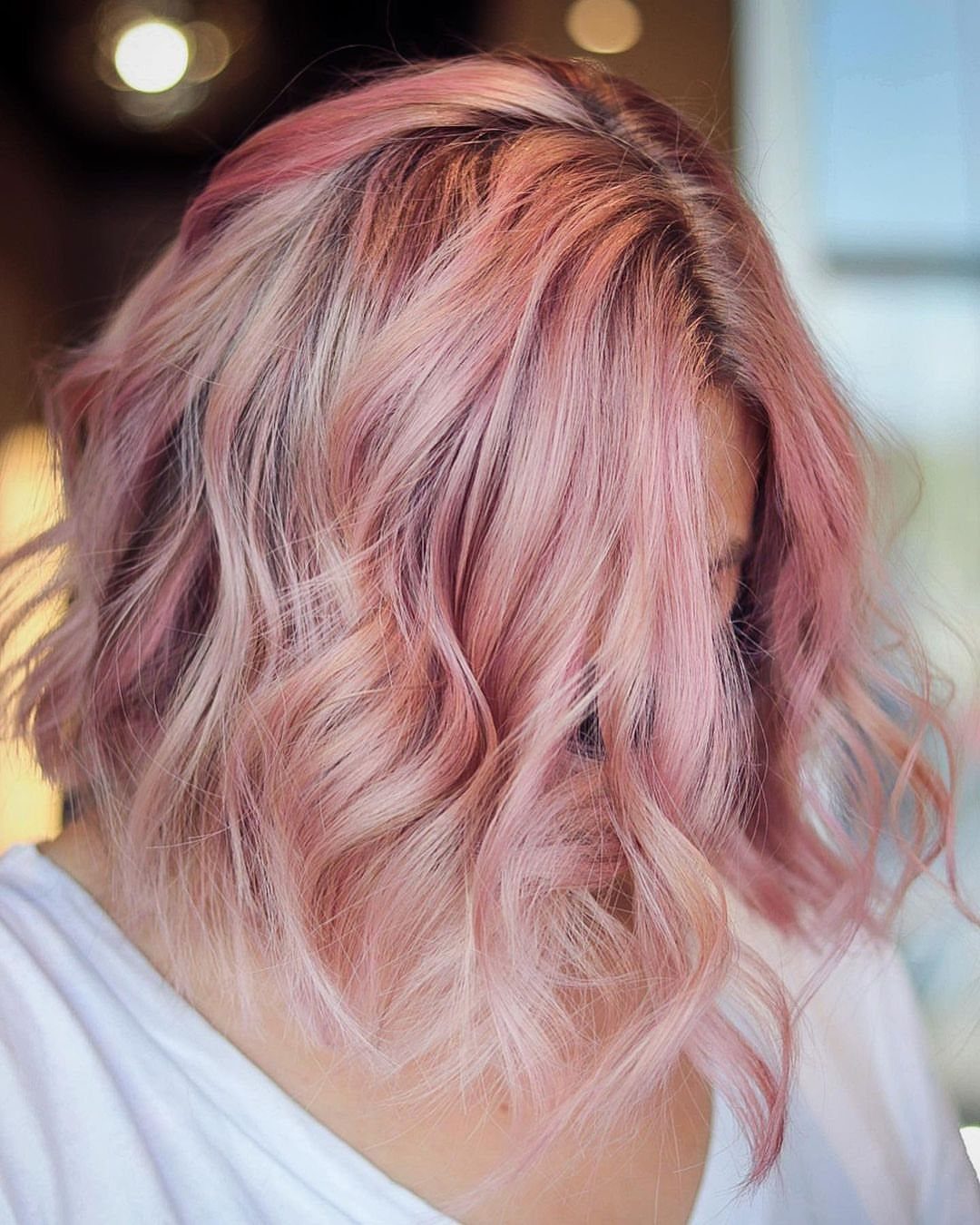 Shoulder-length pastel rose hair falls in soft waves from a side part
