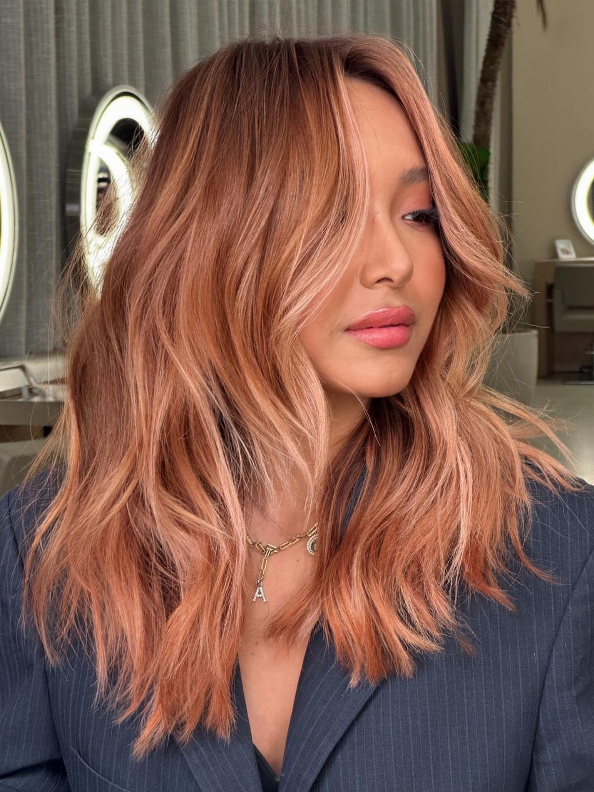 Woman showing peachy rose-gold hair with sweeping bangs and curled-under ends