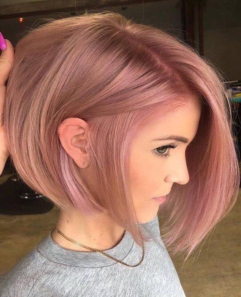 Pale pink blunt bob with darker roots, tucked behind one ear