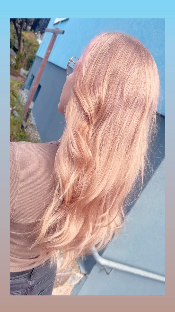 Long rose-gold blonde hair falls in loose waves down a person’s back