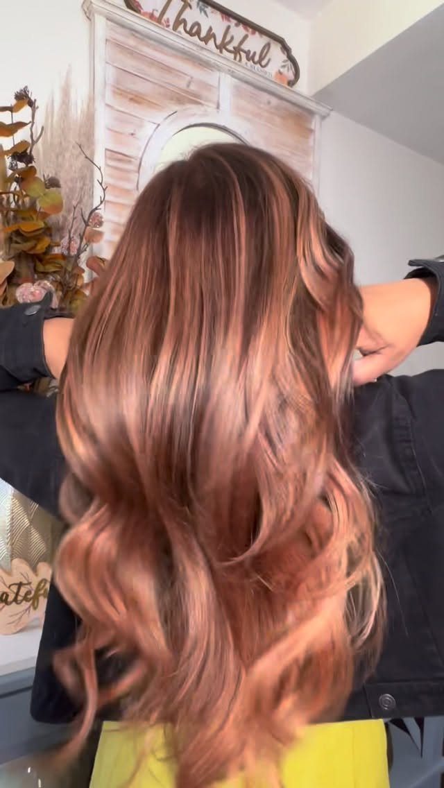 Long wavy hair with dark roots and copper rose-gold balayage curls