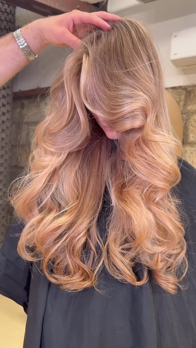 Long rose-gold hair styled in smooth layers with voluminous curled ends