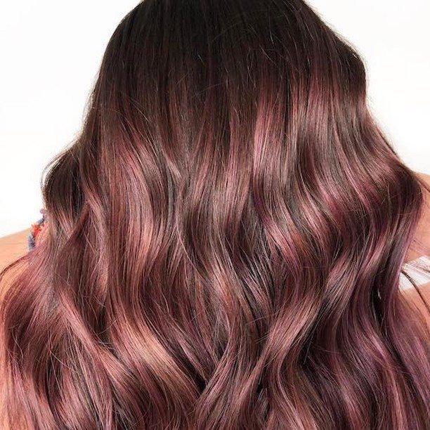 Long wavy hair blending dark roots into muted rose-brown lengths