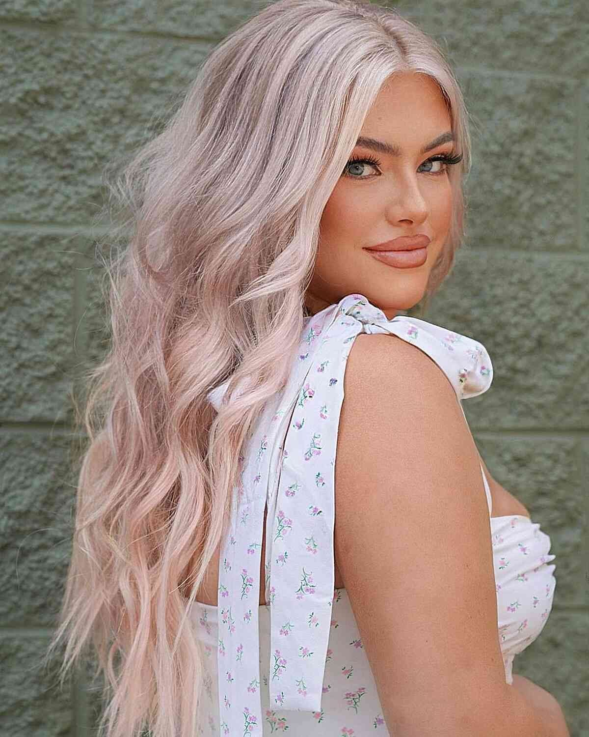 Woman poses with long, wavy pale rose-pink hair