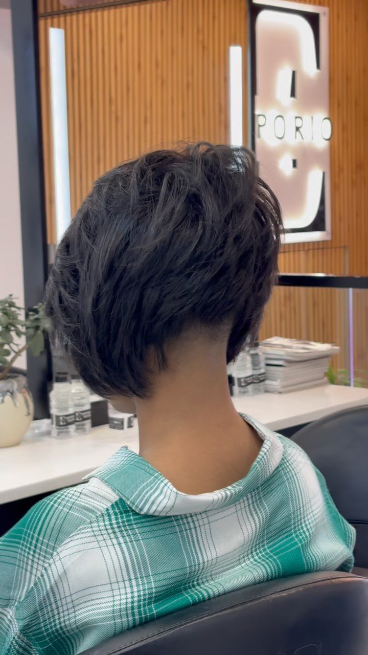 Short dark choppy bob with tousled layers seen from behind in a salon