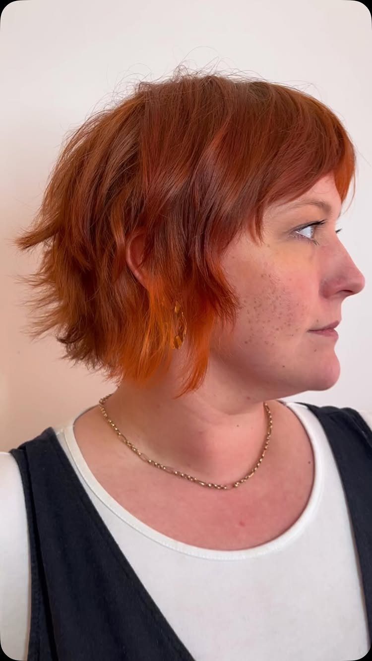 Choppy copper-red pixie bob with layered sides and sweeping bangs