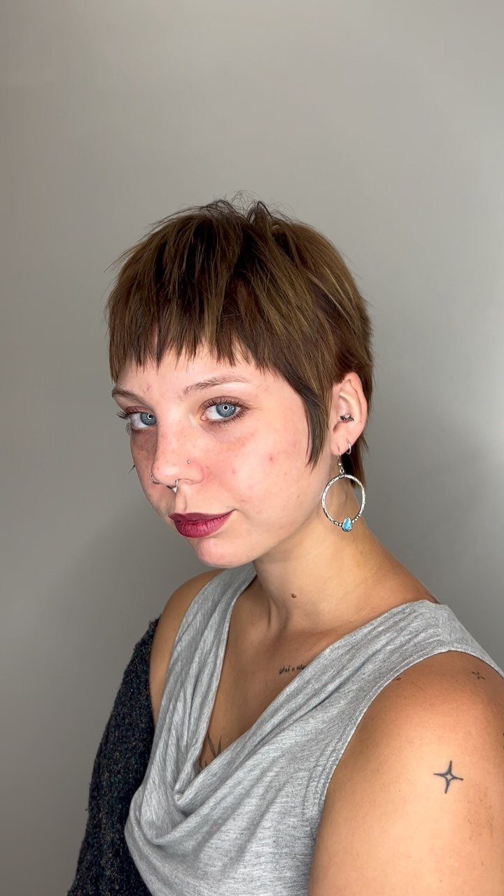 Woman with a short choppy brown pixie haircut and textured fringe