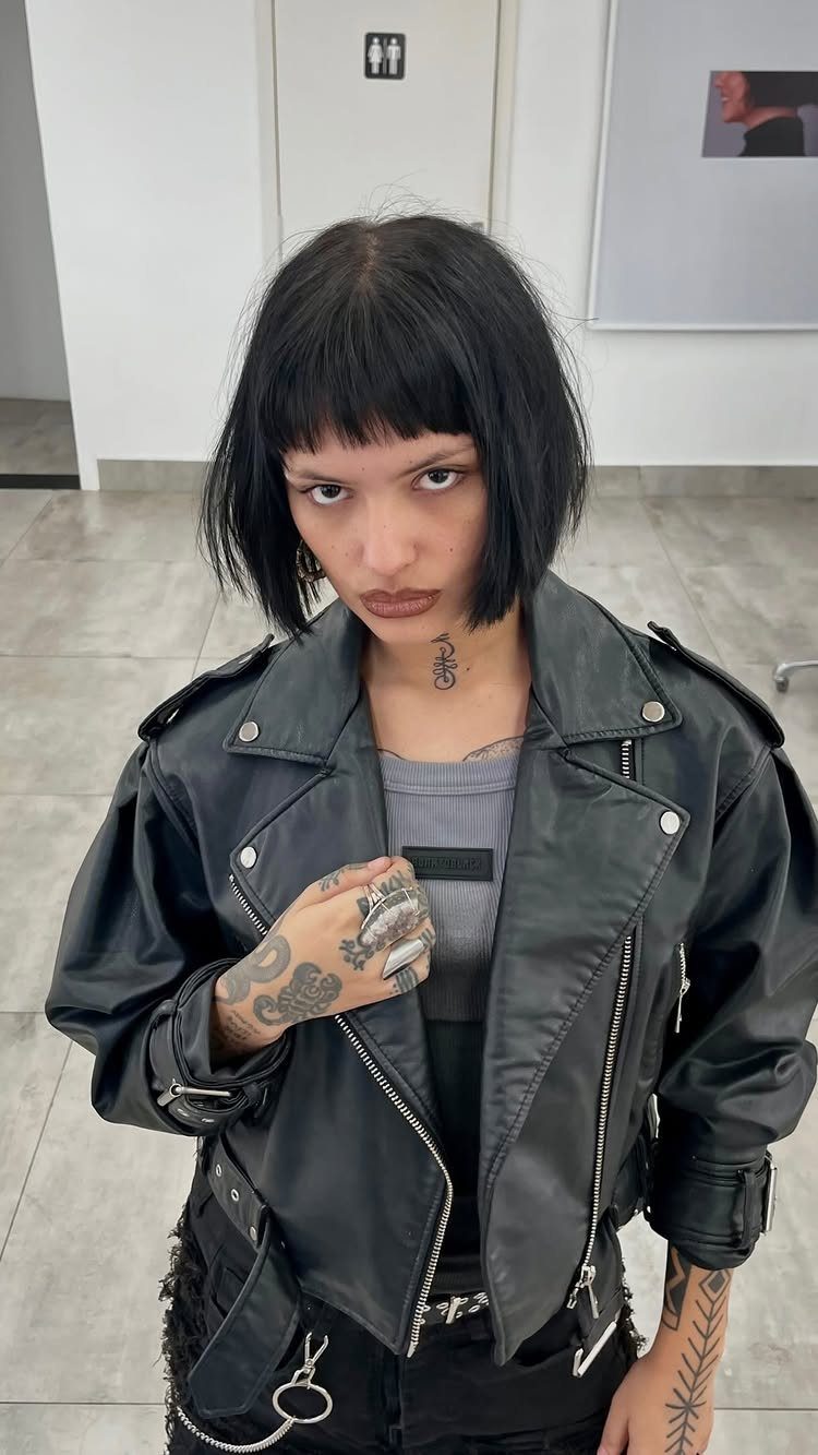 Short black choppy bob with blunt fringe paired with a black leather jacket