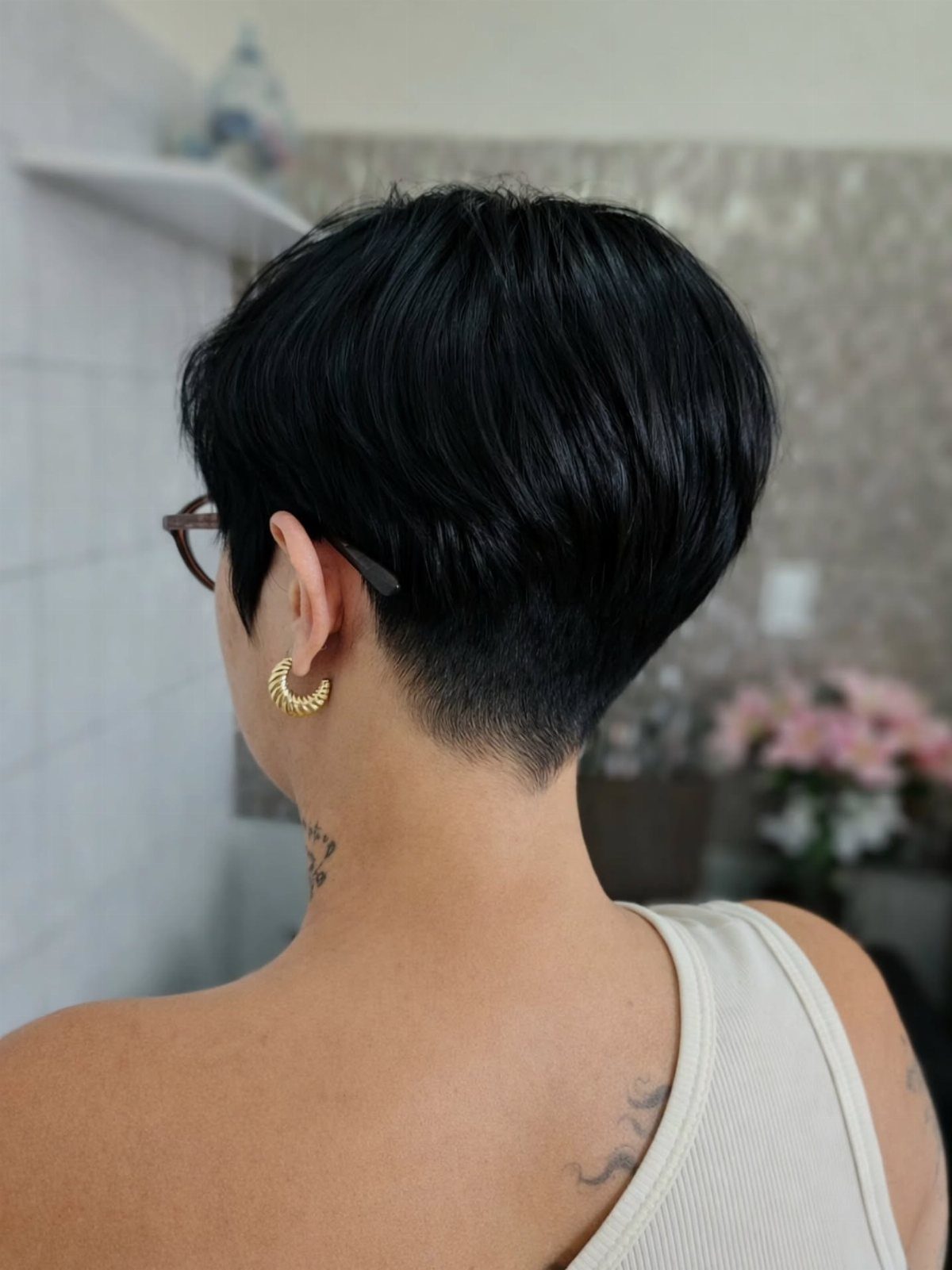 Short black pixie haircut with layered crown and precisely tapered nape