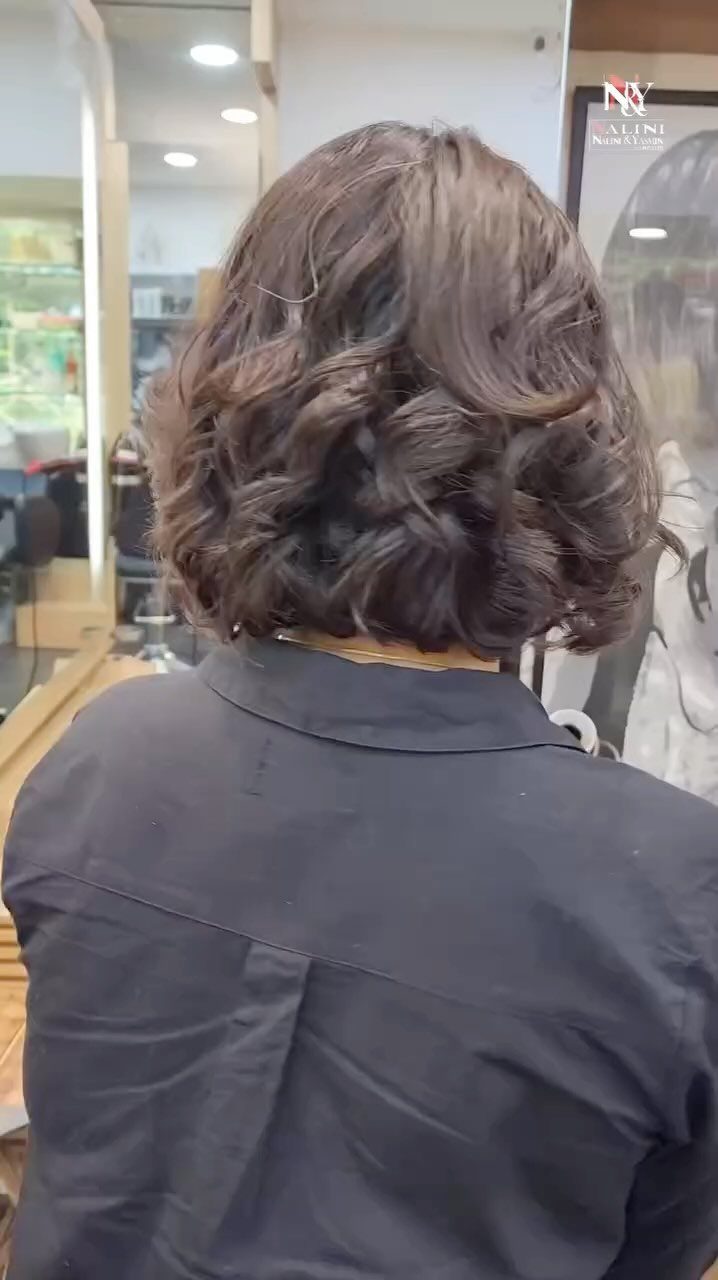 Tousled brown bob with loose curls seen from behind in a salon