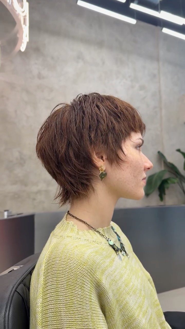 Woman with a voluminous, choppy brown pixie haircut seen in profile