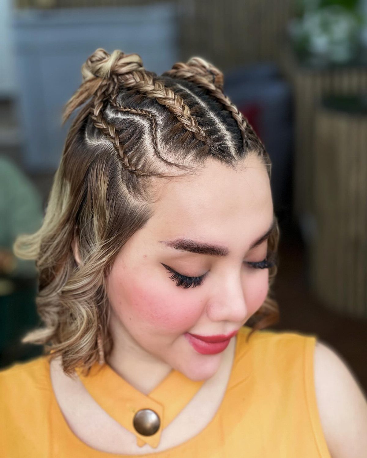 Woman with short highlighted hair braided into a crown and small top knots