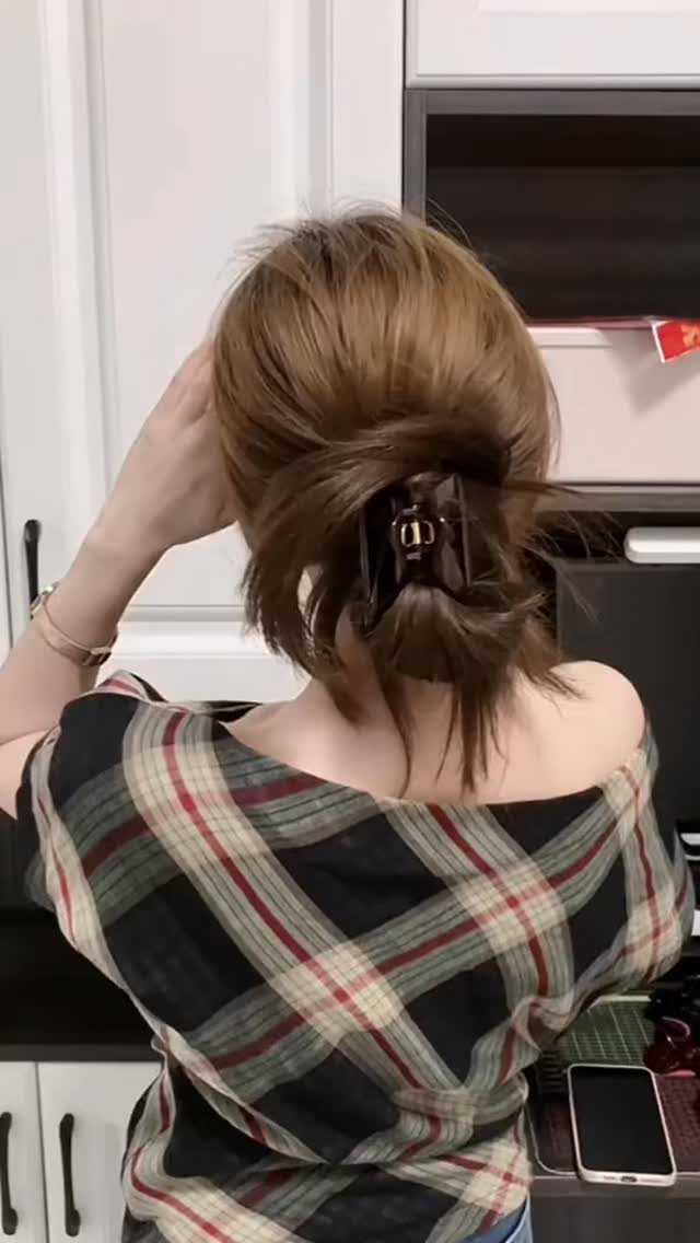 Short brown hair gathered into a loose updo with a black claw clip