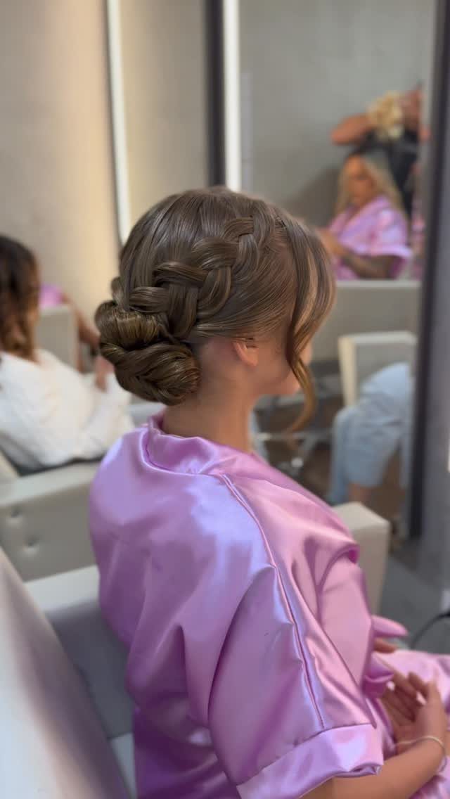 Braided brown hair swept into a low updo on a person in a lavender robe