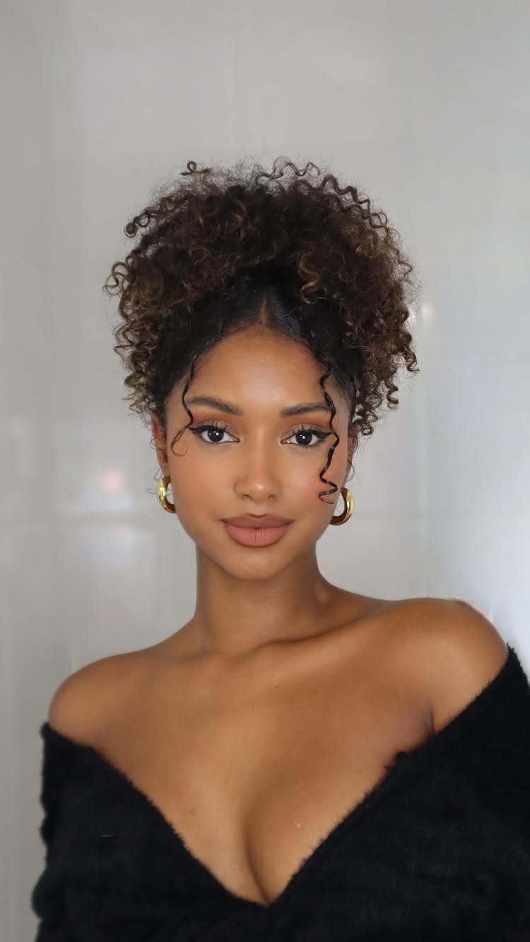 Woman wearing a voluminous high curly updo with loose curls framing her face