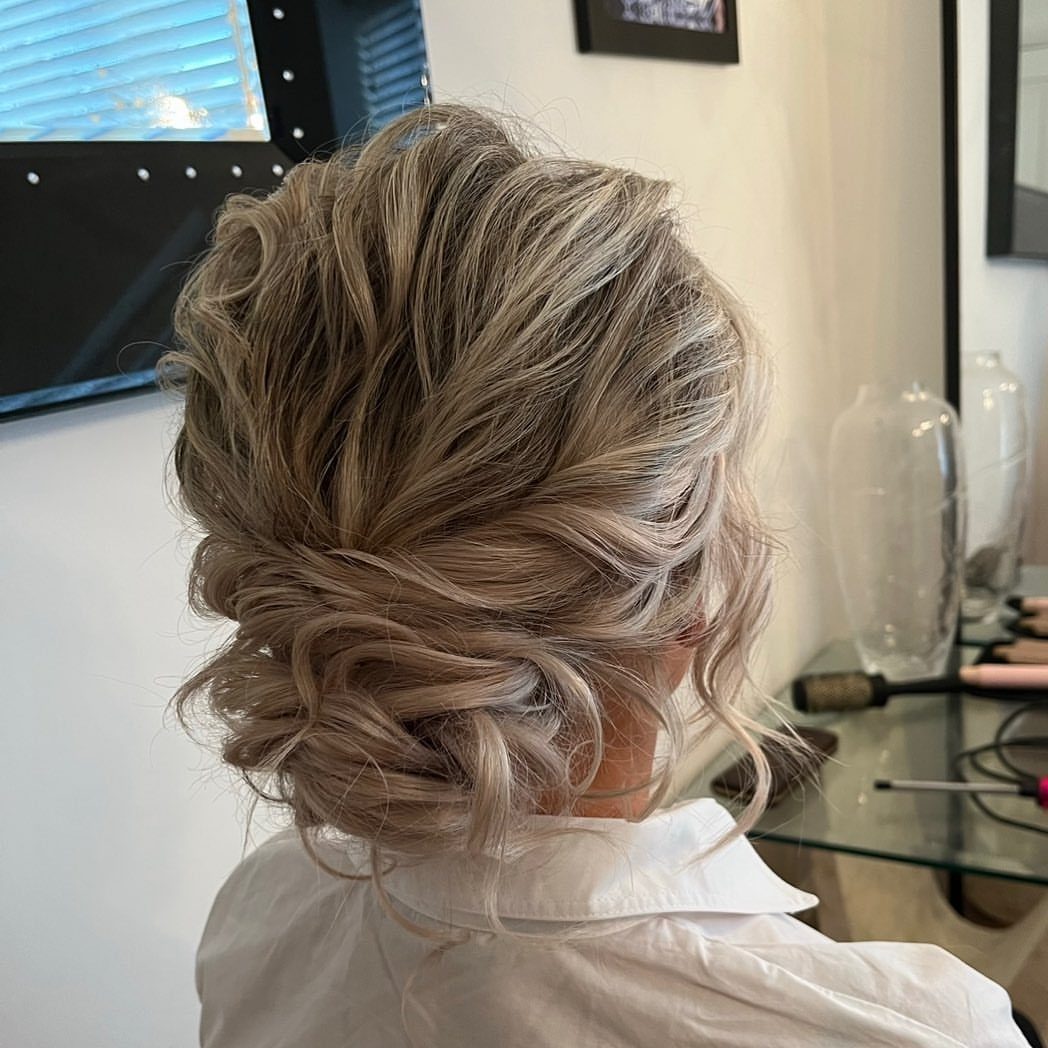 Blonde curled hair gathered into a loose, textured low bun