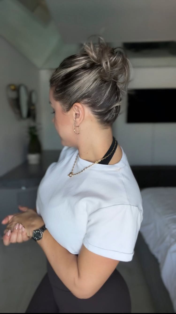Highlighted short hair gathered into a loose, high top knot