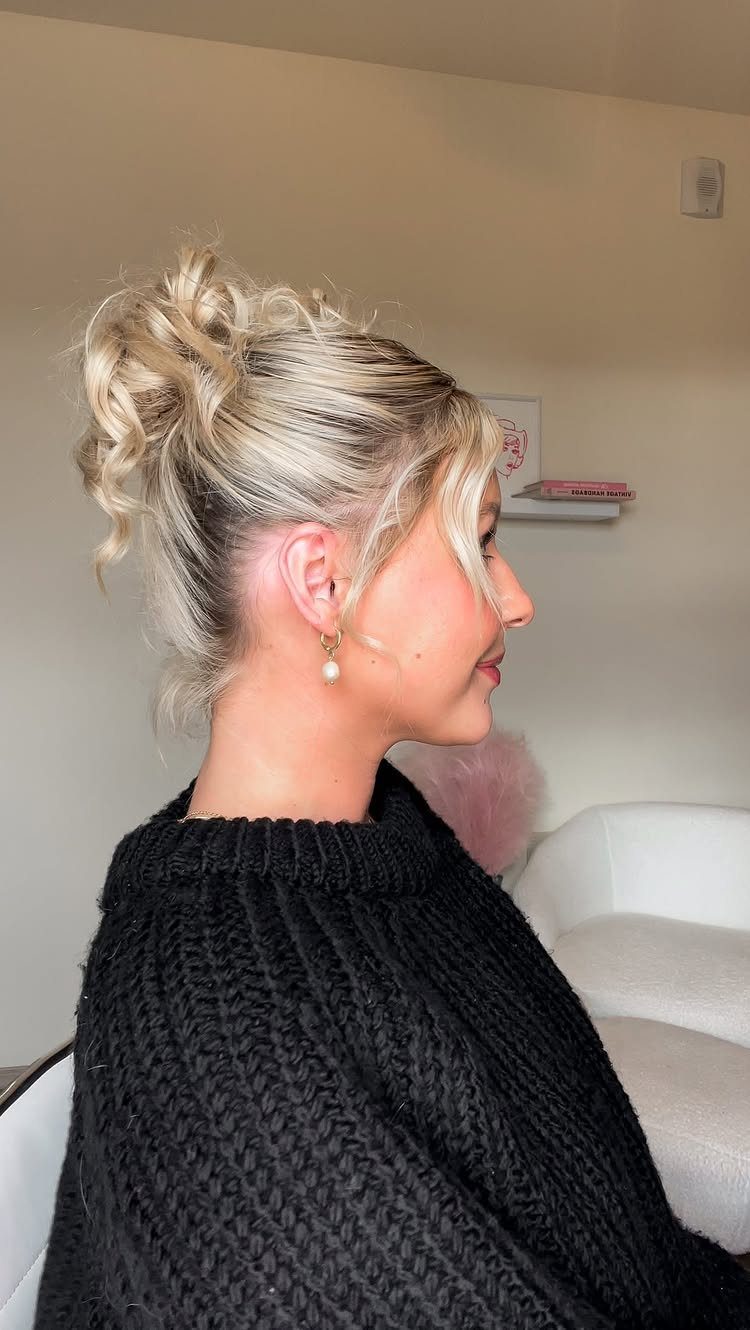 Blonde woman showing a tousled updo with loose curls and face-framing strands