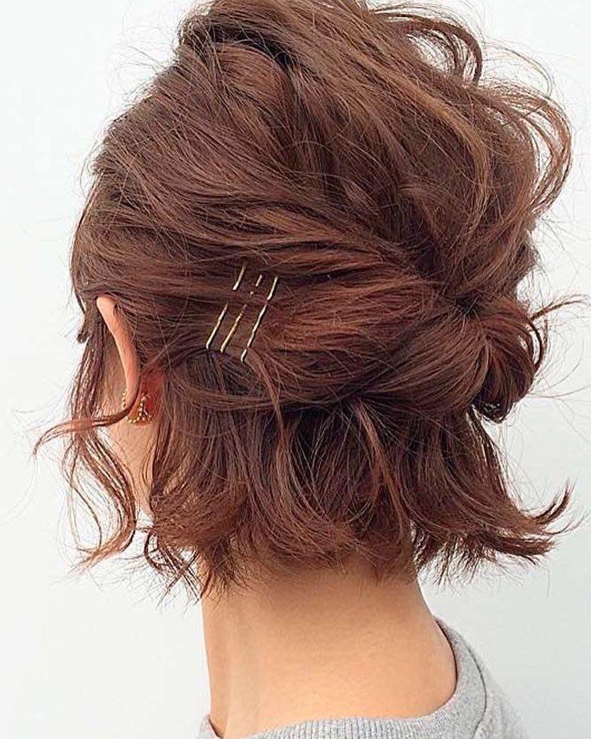 Short reddish-brown hair pinned into a voluminous, loose updo with metal hairpins