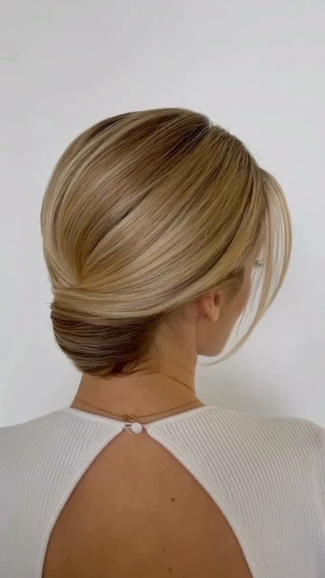 Blonde-haired woman wearing a smooth low updo with a sweeping side fringe