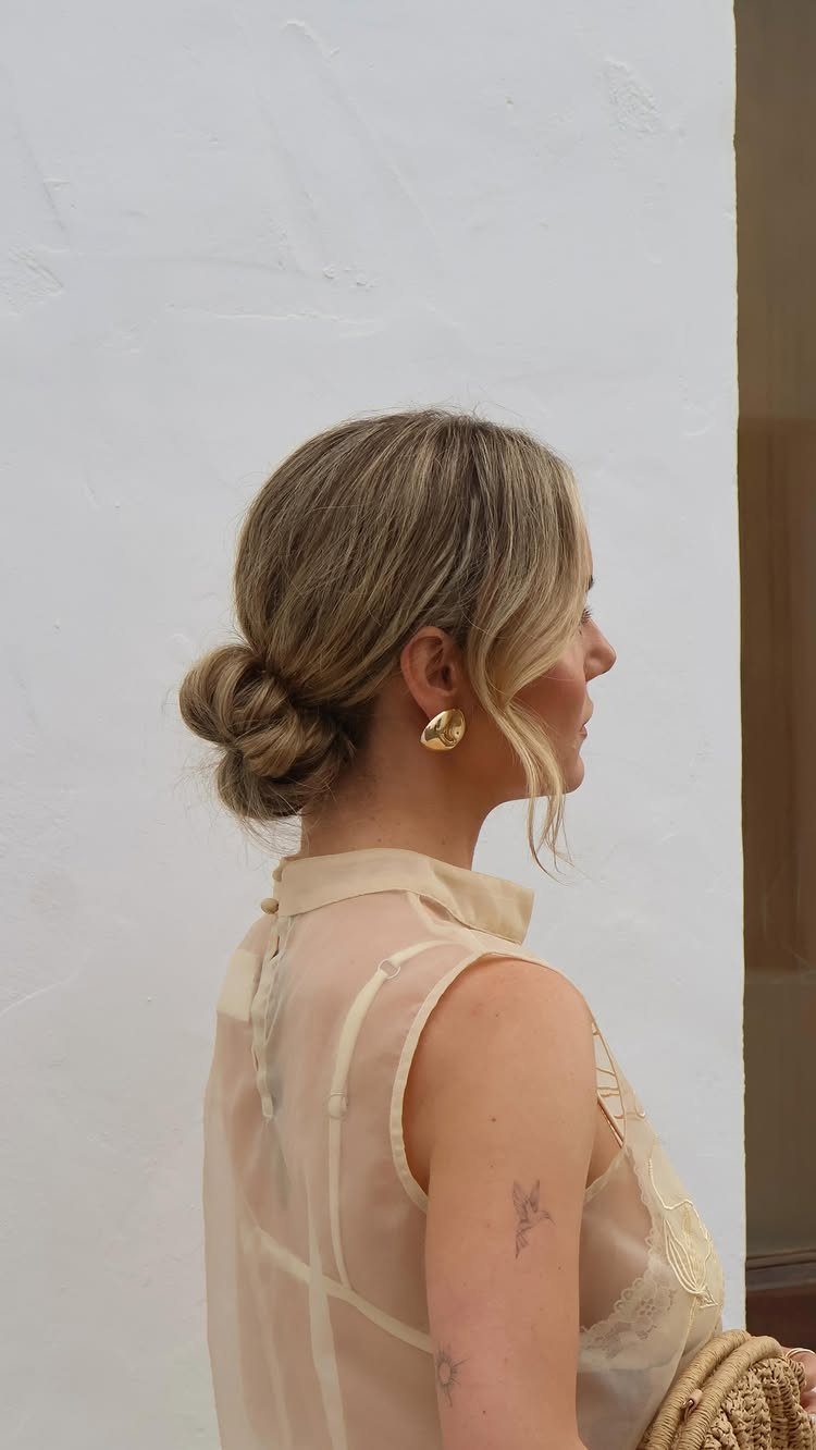 Woman with a loosely twisted low bun and face-framing strands
