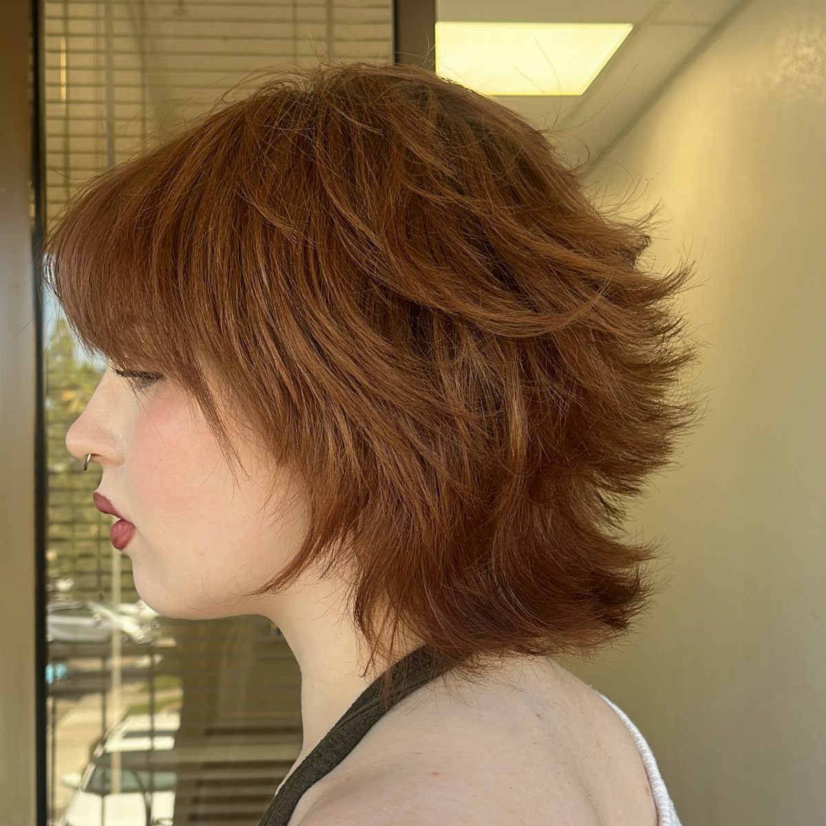 Auburn layered mullet with choppy sides and feathered, shaggy hair at the back