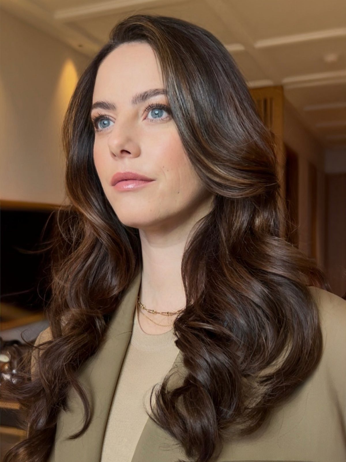 Woman with a center part and long dark hair brushed into voluminous curled ends