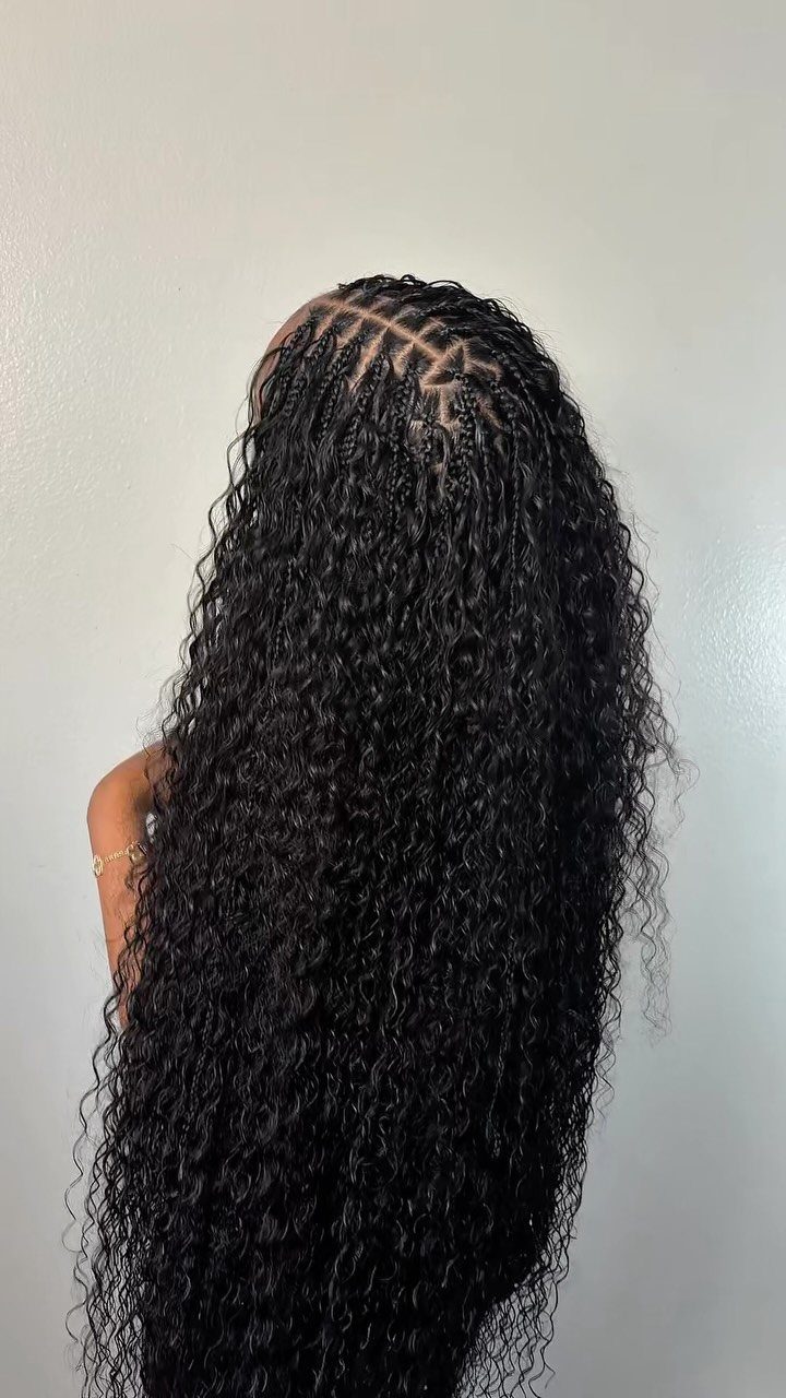 Long black curls with braided rows framing a textured middle part