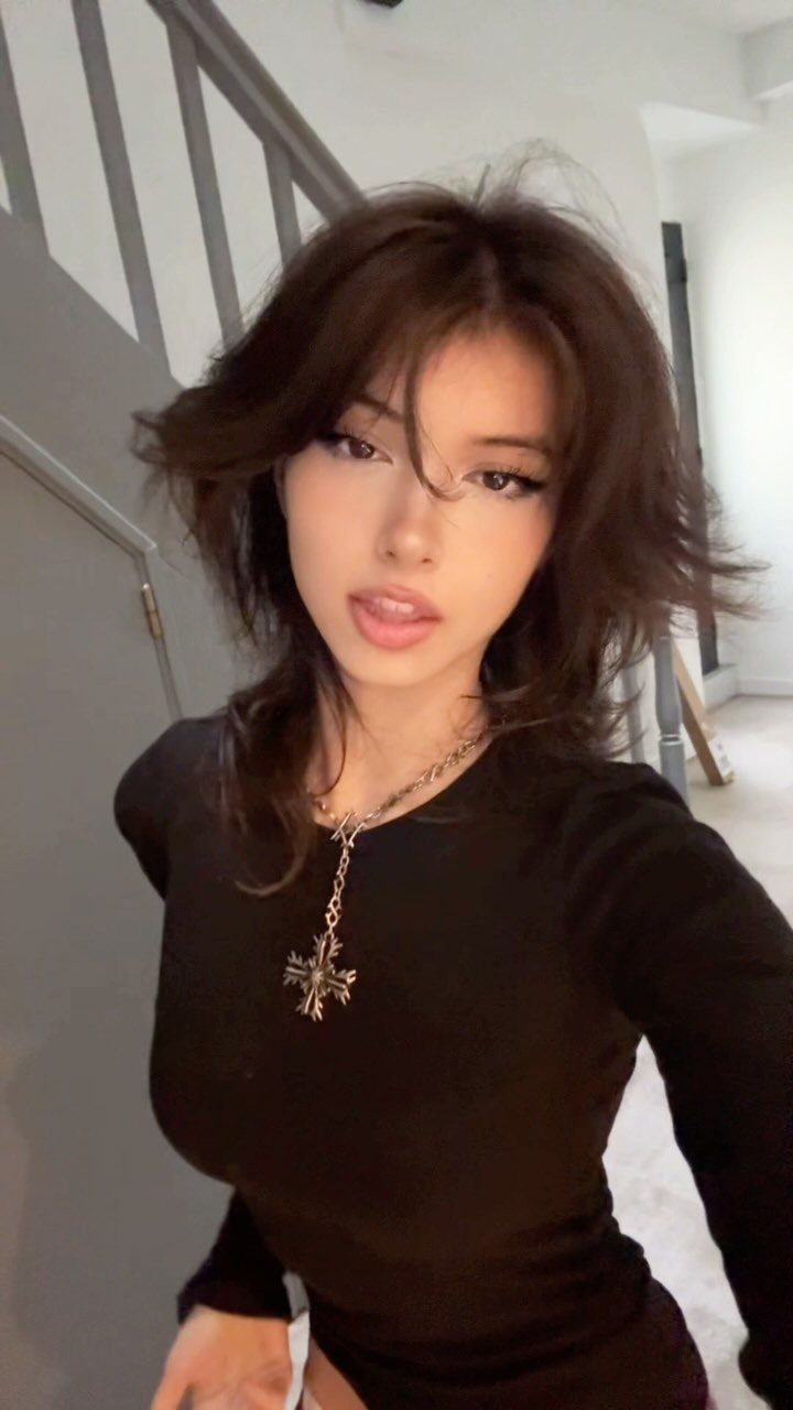 Woman showing a textured middle part in layered, tousled dark brown hair