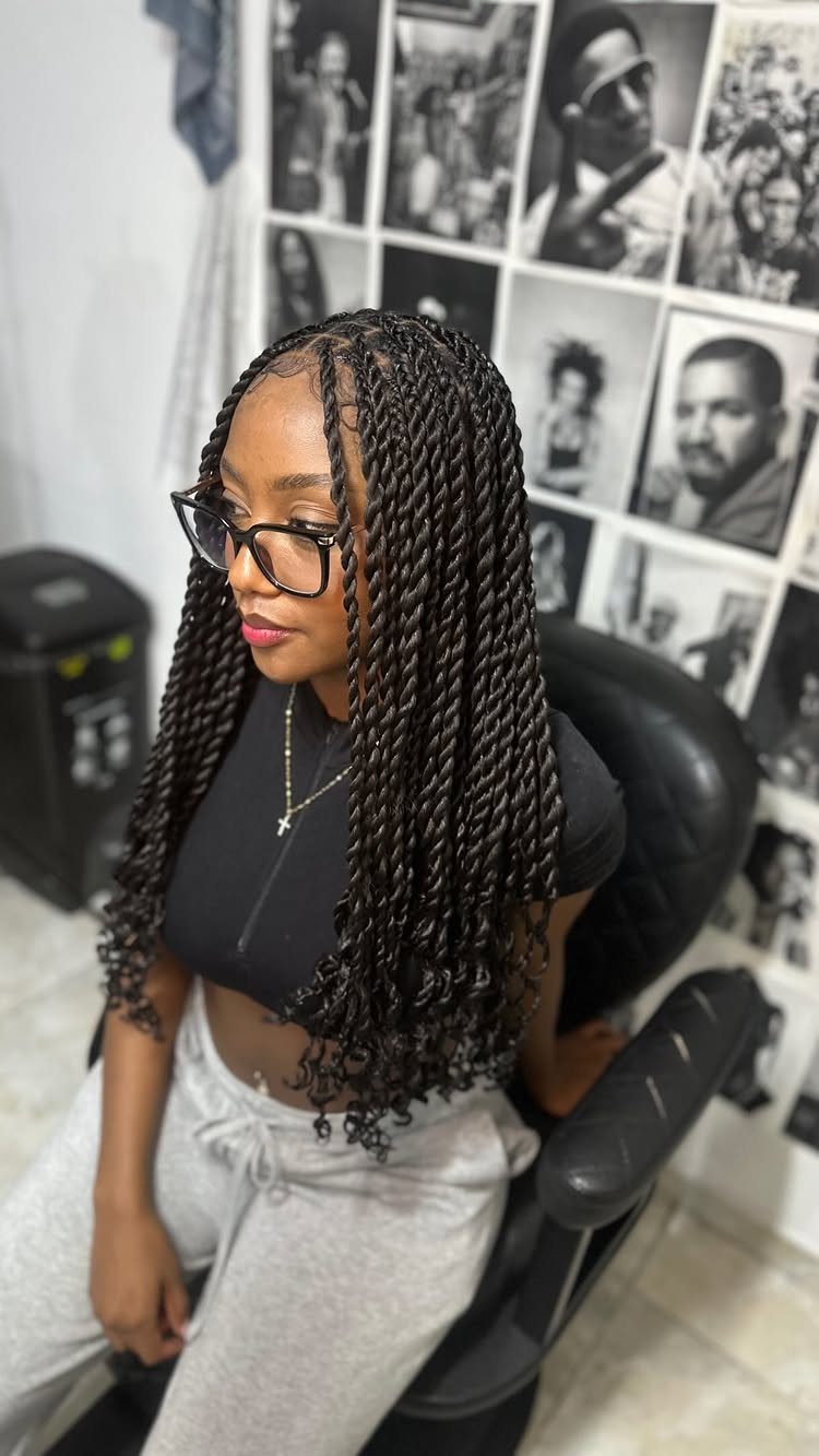 Woman seated in a salon showing long textured twists with a middle part