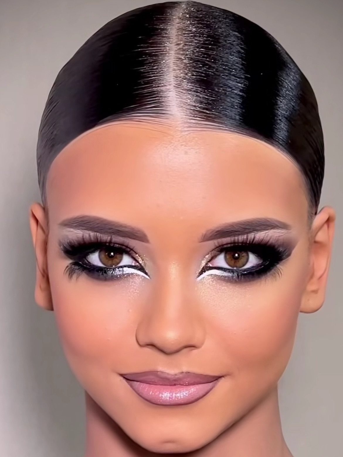 Woman with glossy black hair smoothed flat around a precise center part