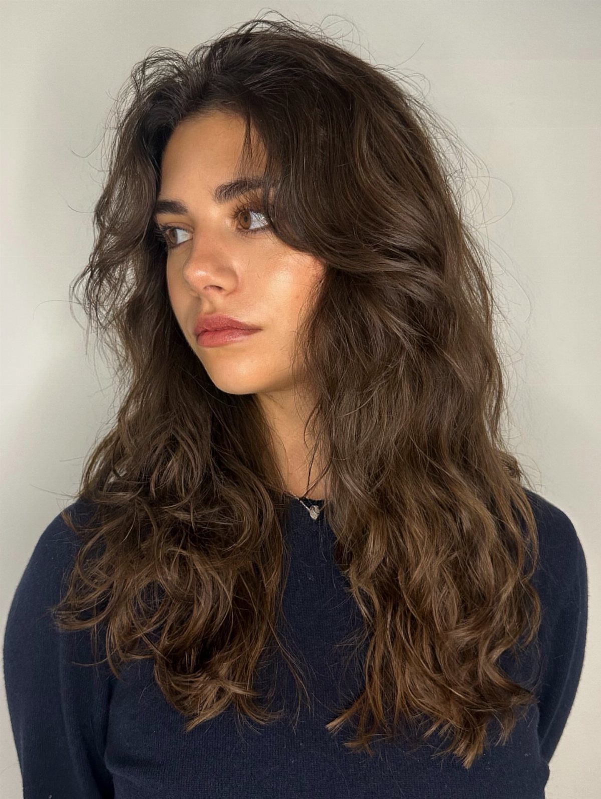 Woman with tousled dark waves parted down the middle