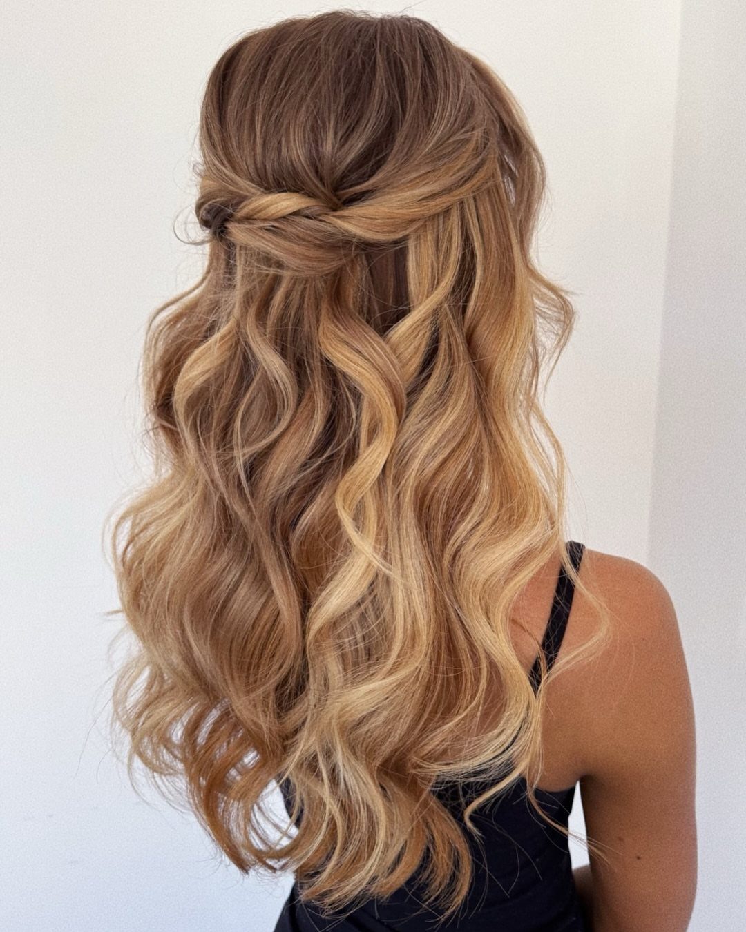 Long wavy blonde hair styled with a twisted half-up detail across the back
