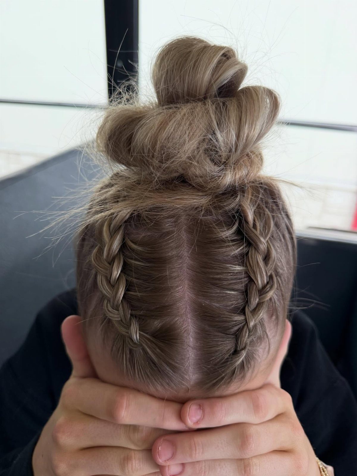 Braided medium brown hair styled into a voluminous high bun