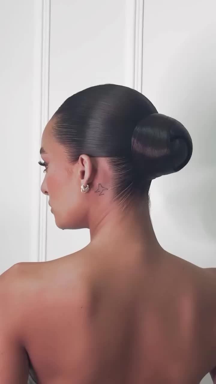 Sleek dark hair gathered into a polished low chignon bun at the nape
