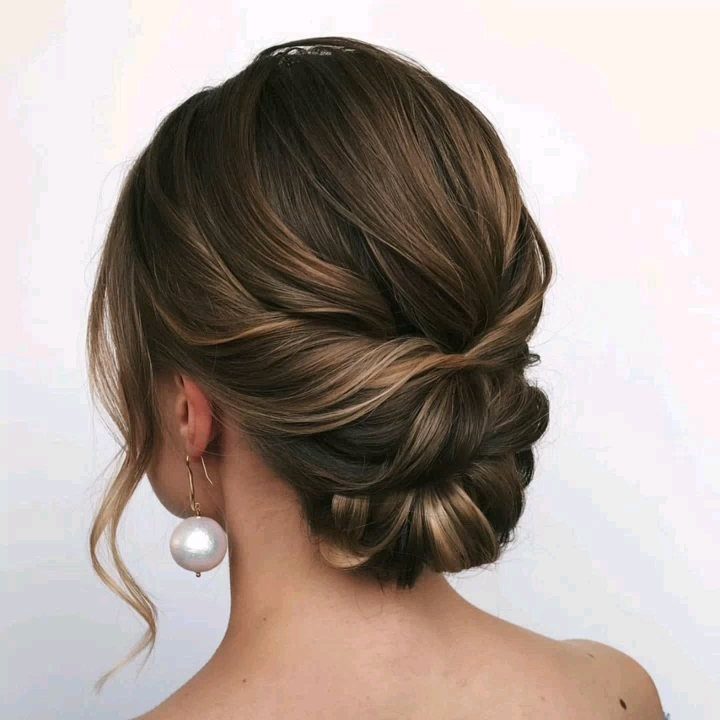 Brown medium hair swept into a low twisted updo with a loose curl