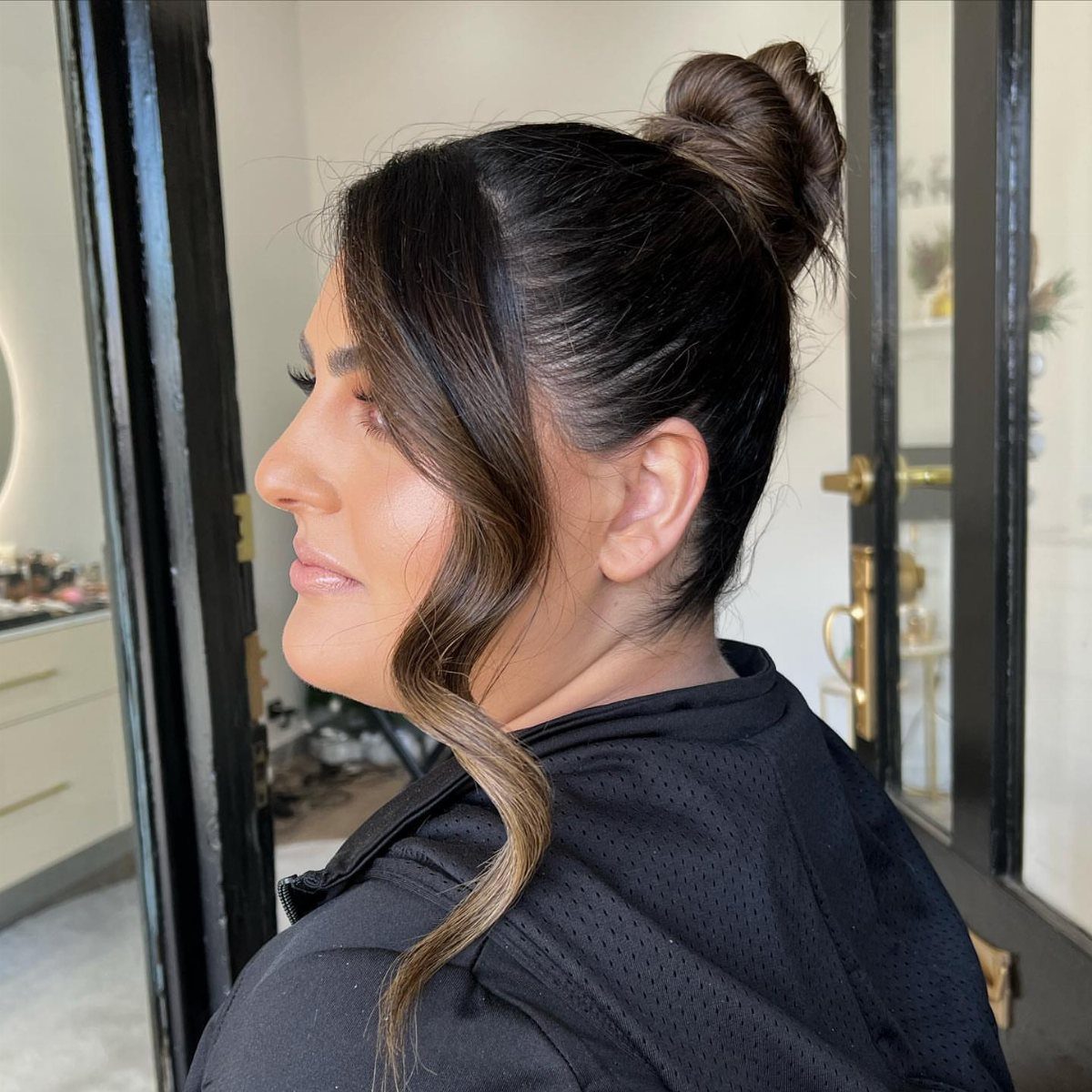 Woman wearing a high, textured bun with curled face-framing strands