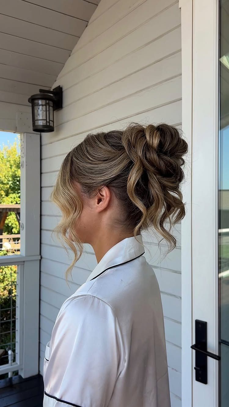 Woman with curled hair pinned into a loose side updo on a porch