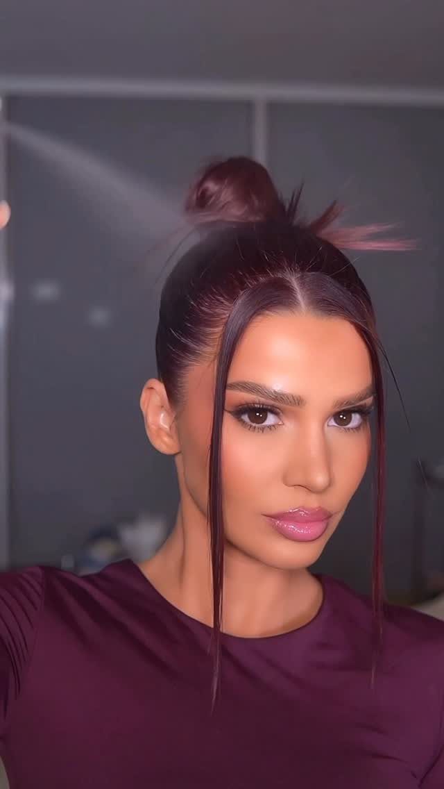 Woman wearing a smooth high bun with two loose face-framing strands