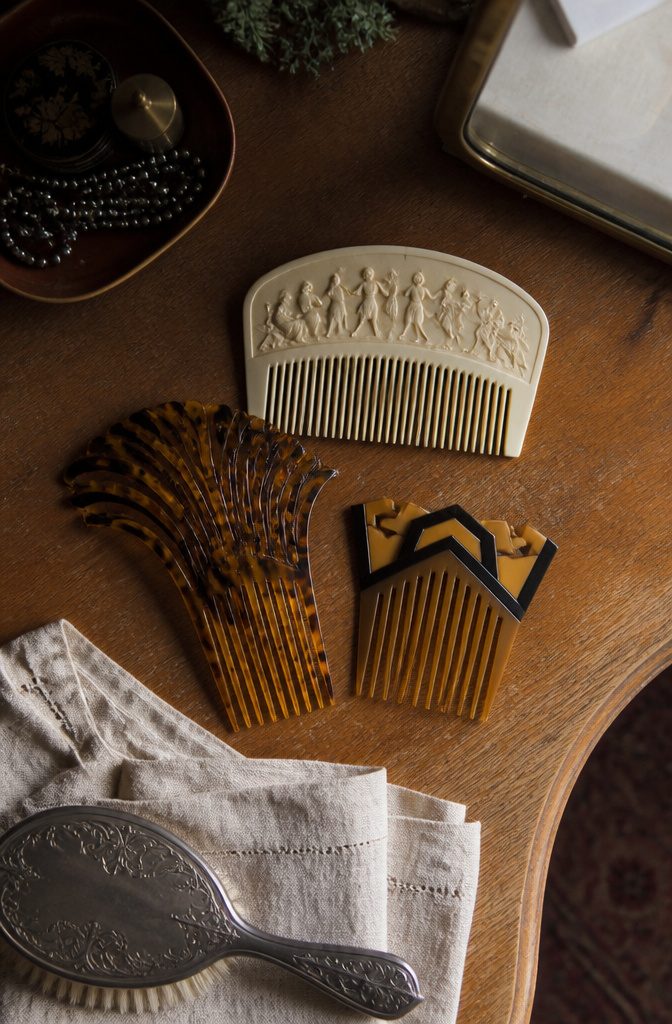 Carved ivory comb beside a bone pin and comb with contrasting shapes